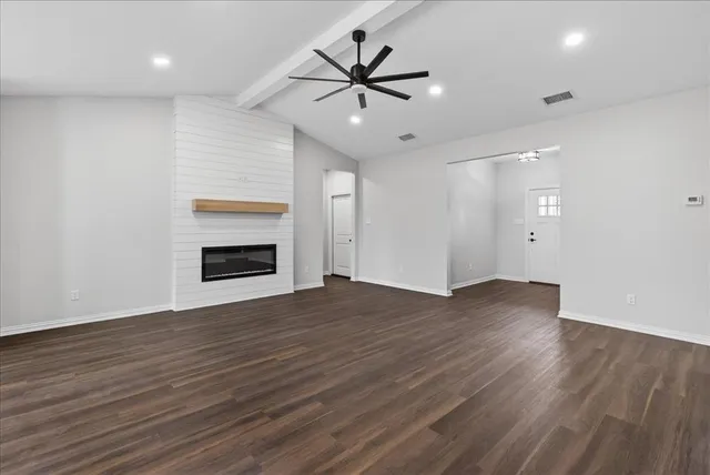 an empty room with wooden floor and ceiling fan