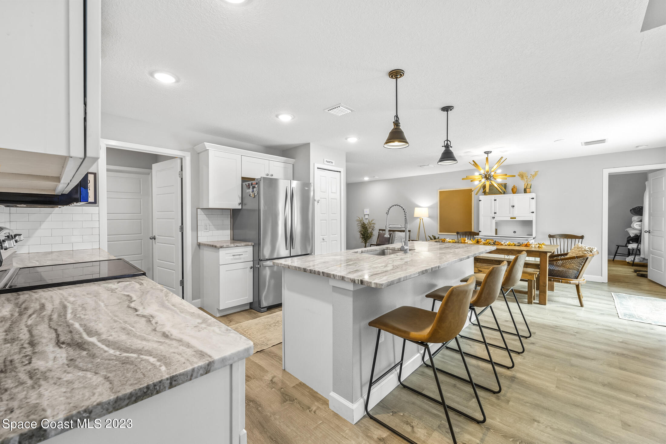 1003 Hayden Road Rockledge, FL 32955 - Photo 8 of 29 a kitchen with stainless steel appliances kitchen island granite countertop a kitchen island a stove a refrigerator a sink and a dining table with chairs