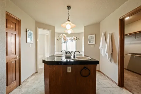 a bathroom with a granite countertop sink a refrigerator and a mirror