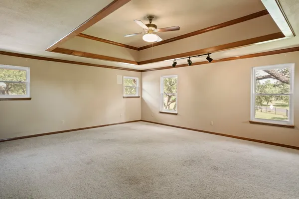 an empty room with windows and fan