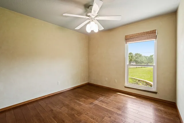 a view of an empty room with window and wooden floor