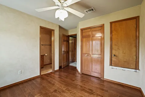 an empty room with wooden floor closet and windows