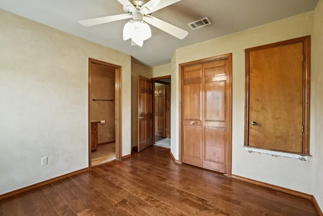 an empty room with wooden floor closet and windows
