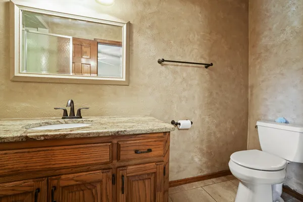 a bathroom with a granite countertop sink toilet and a mirror