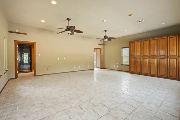 an empty room with chandelier fan and windows