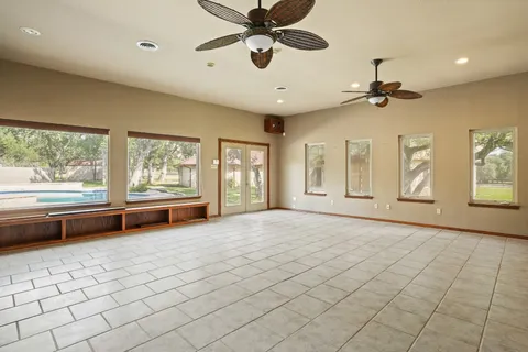 a view of an empty room with a window and kitchen view