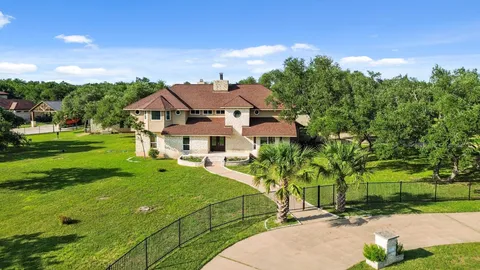a view of a white house with a big yard plants and large trees