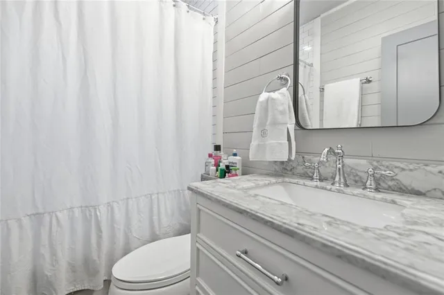 a bathroom with a granite countertop sink vanity mirror and toilet