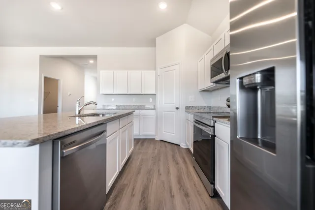 a kitchen with stainless steel appliances granite countertop a refrigerator a stove and a sink