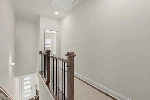 a view of a hallway with wooden floor and a bathroom