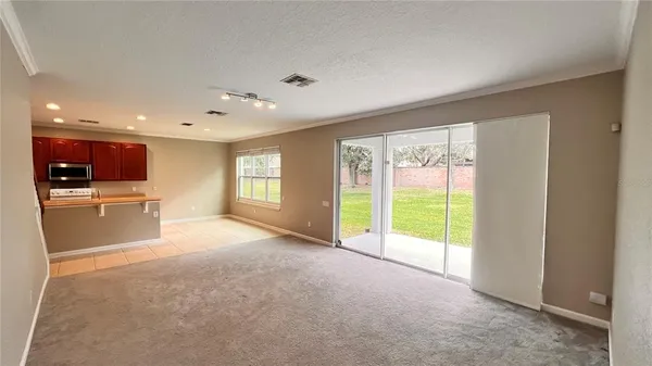 a view of an empty room with a kitchen view and a window