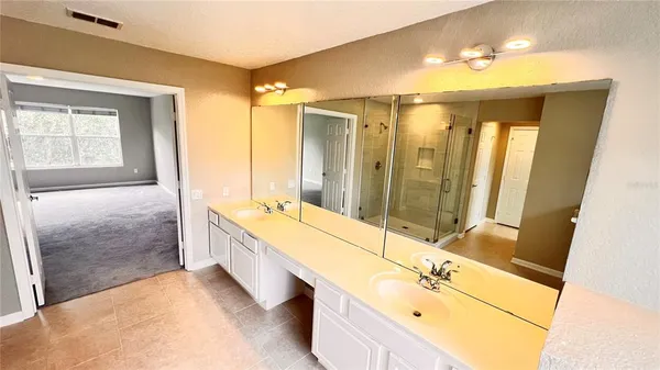 a bathroom with a double vanity sink and mirror with bathtub