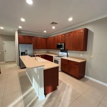 a kitchen with kitchen island granite countertop a sink a stove top oven a refrigerator and cabinets with wooden floor