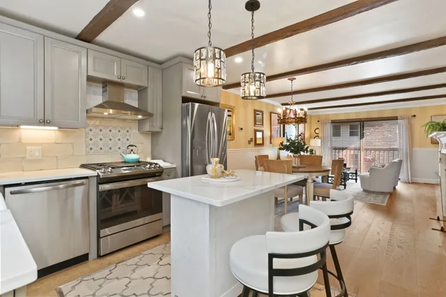 a kitchen with stainless steel appliances granite countertop a sink a stove a refrigerator dining table and chairs