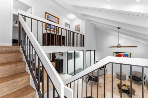 a view of staircase with lots of frames on wall and wooden floor