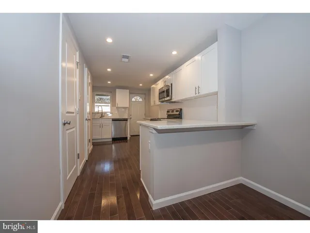 a open kitchen with white cabinets and wooden floor