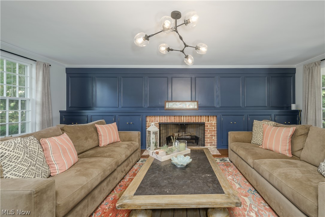 2447 Covington Road Akron, OH 44313 - Photo 9 of 46 Living room featuring ornamental wall with built-in cabinets, brick fireplace, hardwood flooring, and modern chandelier
