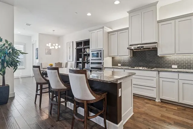 a kitchen with granite countertop white cabinets and stainless steel appliances