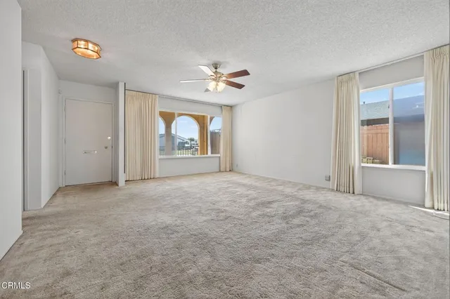an empty room with windows and ceiling fan