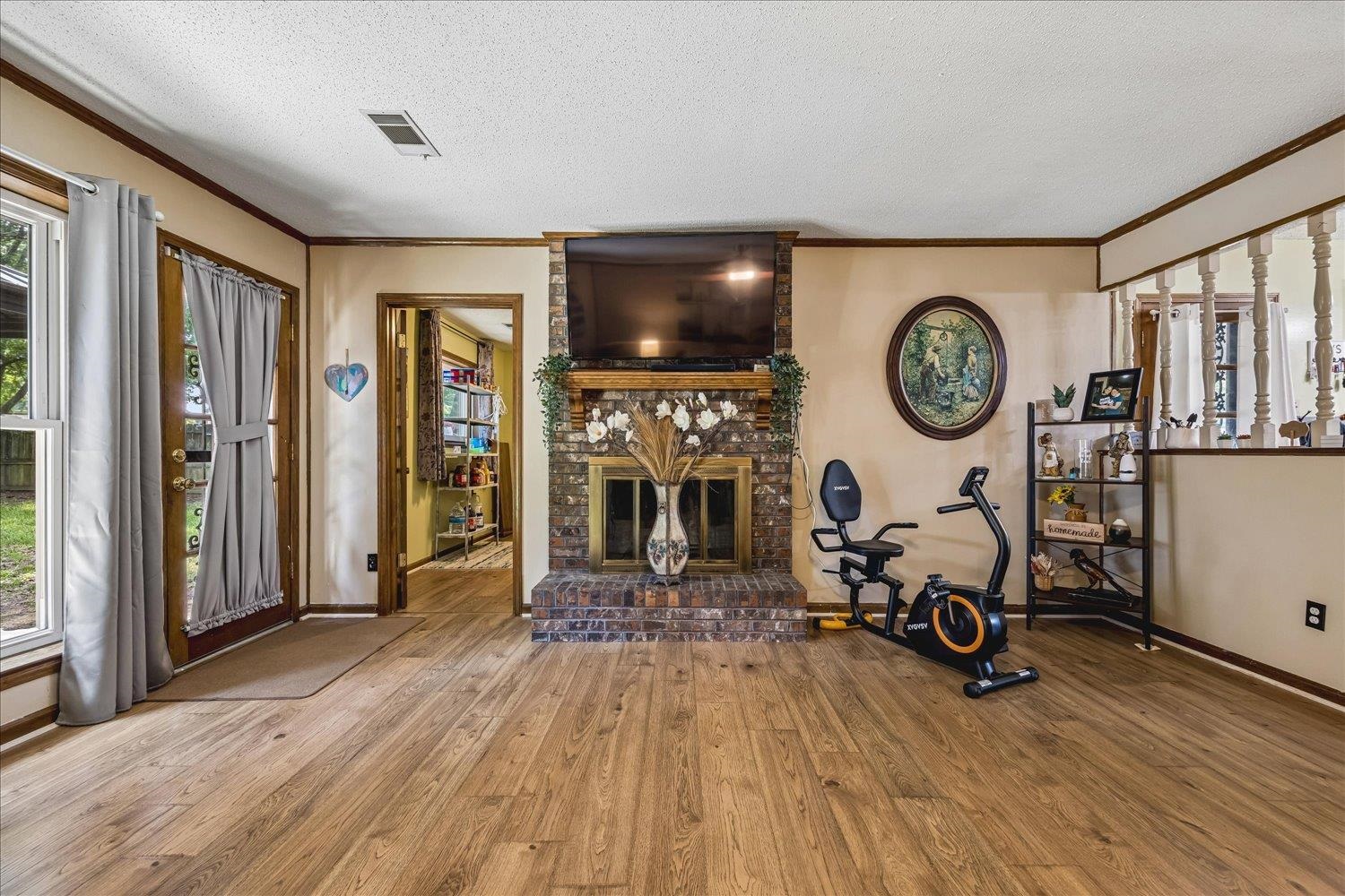 3284 Altruria Road Bartlett, TN 38134 - Photo 9 of 28 Living area featuring wood-finish flooring, a brick fireplace with a wood mantle, and a glass-paneled door opening to outdoor space