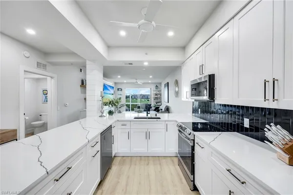 a kitchen with white cabinets appliances and a sink