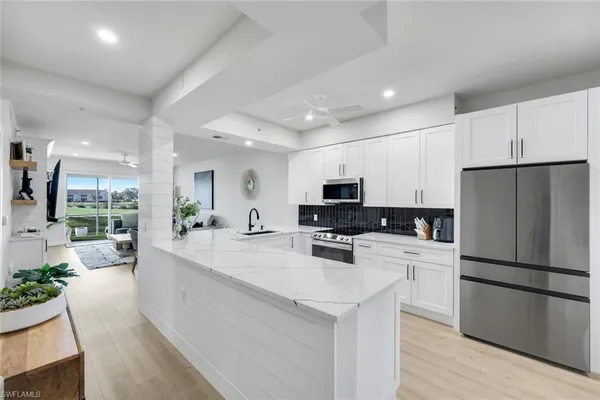 a large kitchen with stainless steel appliances a refrigerator a stove a sink dishwasher a oven with a dining table and chairs with wooden floor