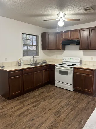 a kitchen with stainless steel appliances granite countertop a sink a stove a refrigerator cabinets and wooden floor