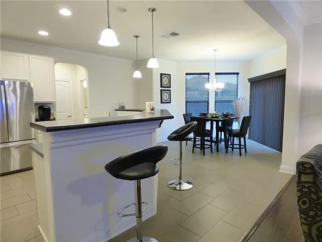 a kitchen with stainless steel appliances kitchen island granite countertop a sink a microwave a refrigerator and chairs