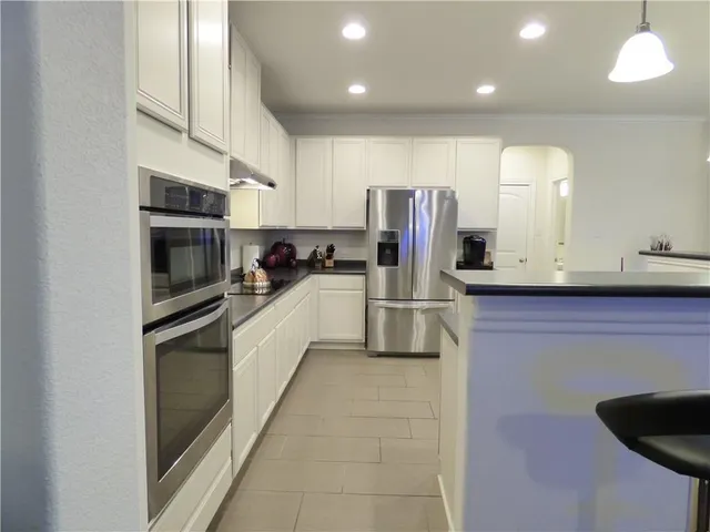 a kitchen with stainless steel appliances granite countertop a refrigerator and a stove