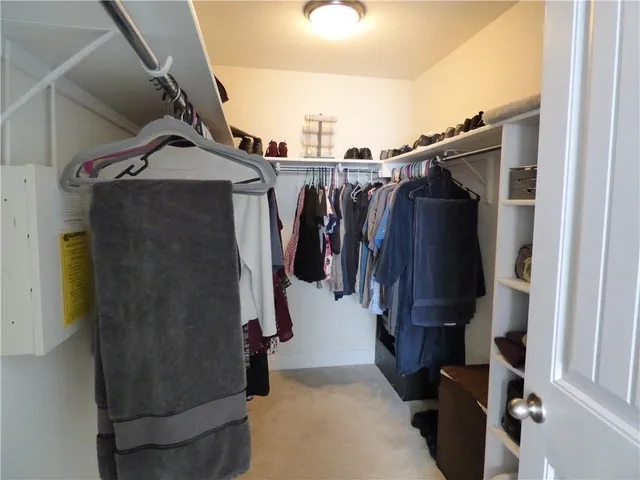 a view of walk in closet with clothes and shoes