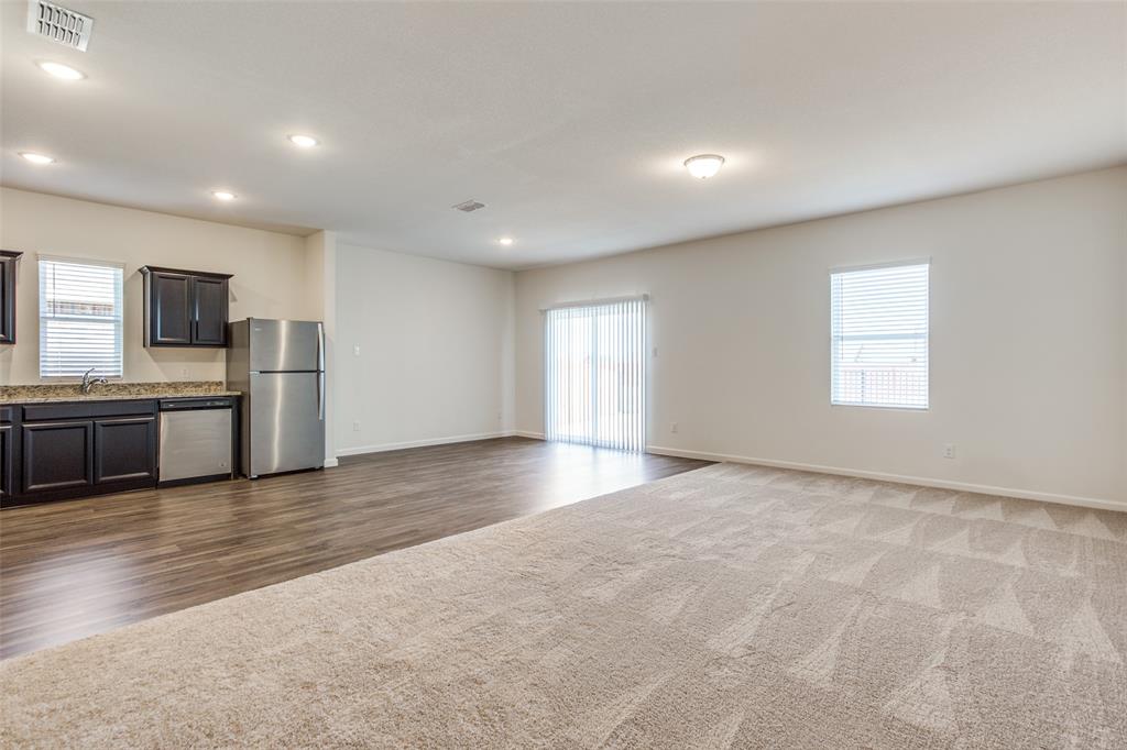 1819 Wolf Run Anna, TX 75409 - Photo 2 of 11 Open-concept living area featuring a kitchen with dark cabinetry, stainless steel appliances, and a wood-finish floor