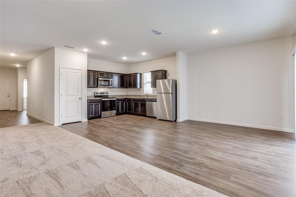 1819 Wolf Run Anna, TX 75409 - Photo 3 of 11 Open-concept living space featuring a modern kitchen with dark cabinetry and stainless steel appliances