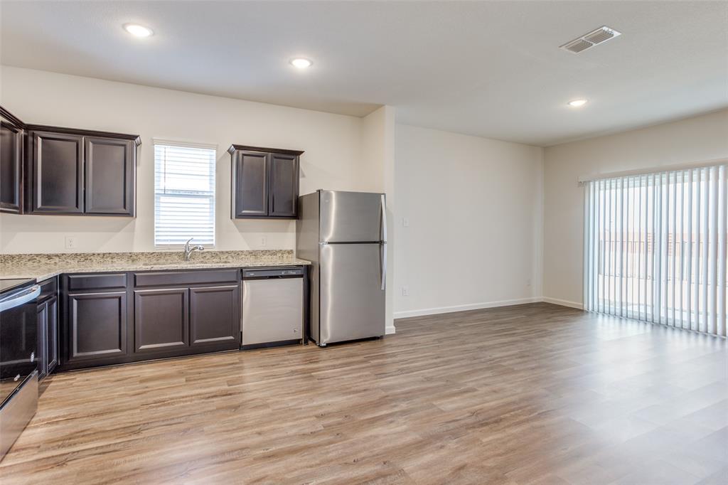 1819 Wolf Run Anna, TX 75409 - Photo 6 of 11 Open-concept kitchen and living area featuring wood-finish flooring, dark wood cabinetry, and light-colored countertops