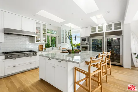 a kitchen with stainless steel appliances granite countertop a stove a sink and white cabinets with wooden floor