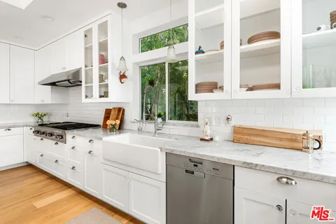 a kitchen with stainless steel appliances granite countertop a sink a stove and a wooden floor
