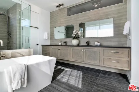 a spacious bathroom with a double vanity sink a mirror and a bathtub