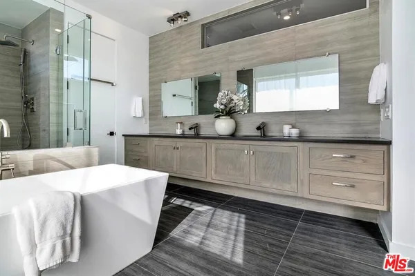 a spacious bathroom with a double vanity sink a mirror and a bathtub