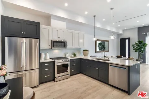 a kitchen with stainless steel appliances granite countertop a refrigerator a stove a sink and a microwave