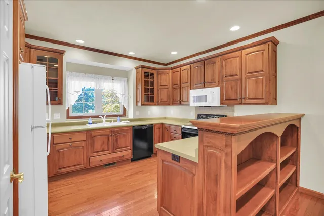 a kitchen with stainless steel appliances granite countertop wooden cabinets a stove top oven a sink and dishwasher with wooden floor