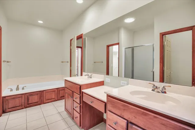 a bathroom with a sink double vanity granite tub shower and a mirror