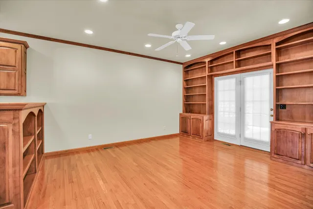 a view of empty room with wooden floor and fan