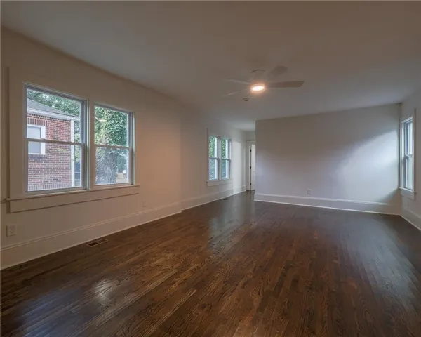a view of an empty room with wooden floor and a window