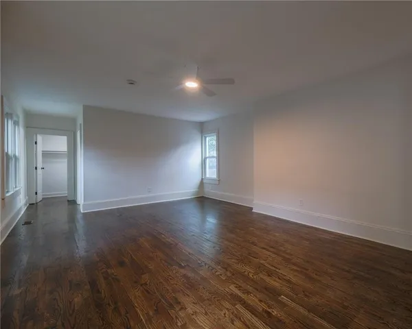 a view of empty room with wooden floor and fan