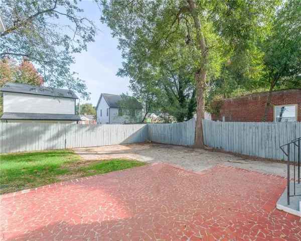a backyard of a house with plants and large trees