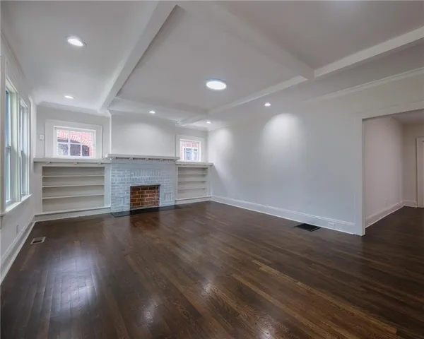 an empty room with wooden floor fireplace and window