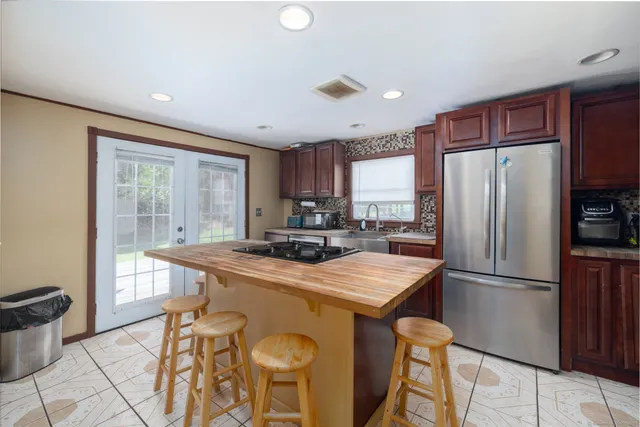 a kitchen with stainless steel appliances granite countertop a refrigerator a sink a stove a dining table and chairs