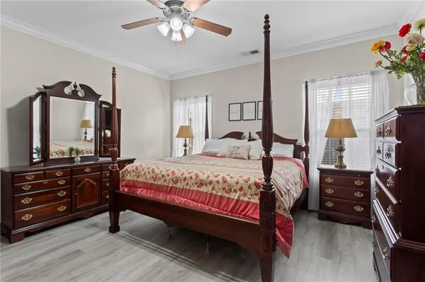 a bedroom with a bed a chandelier and a flat tv screen on dresser