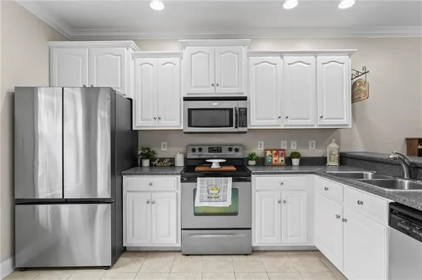 a kitchen with stainless steel appliances granite countertop white cabinets and a refrigerator