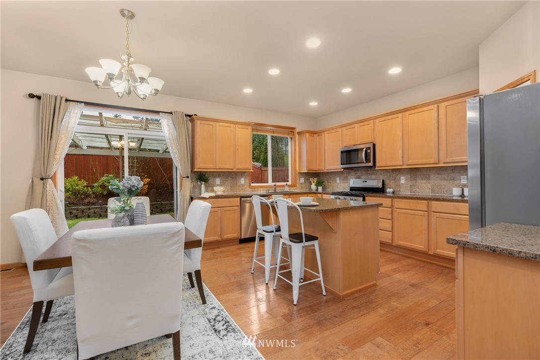 3616 Mill Place South Renton, WA 98055 - Photo 4 of 25 a kitchen with granite countertop a stove top oven a sink dishwasher a dining table and chairs with wooden floor