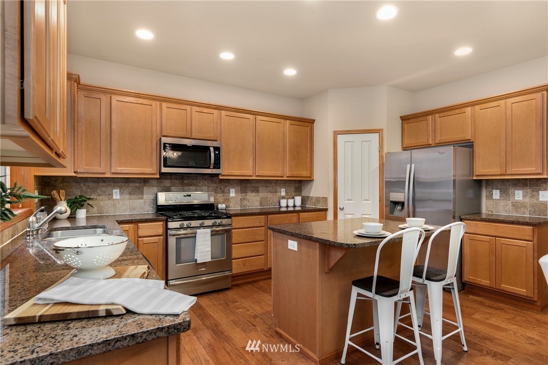 3616 Mill Place South Renton, WA 98055 - Photo 7 of 25 a kitchen with stainless steel appliances granite countertop a stove top oven a sink a dining table and chairs